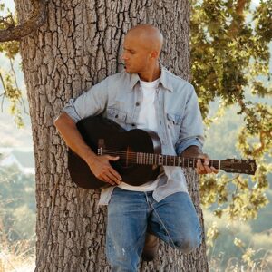 Milow mit Gitarre an einem Baum